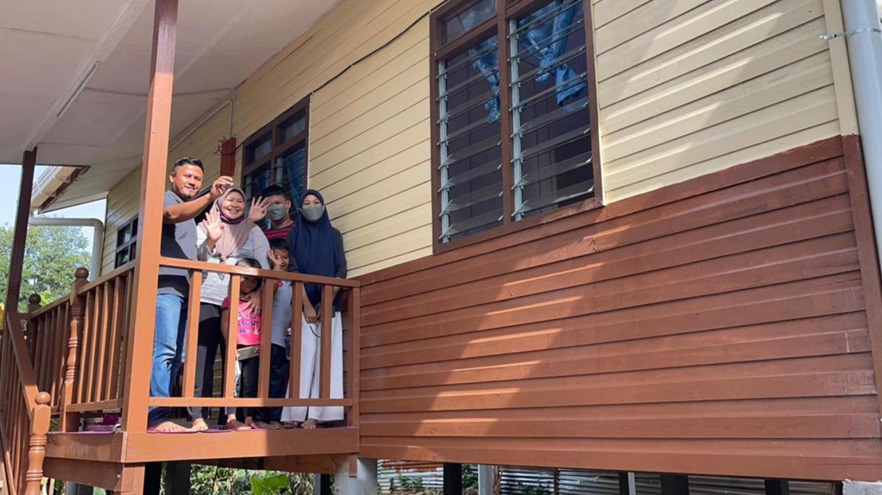 Penerima PPRT Jumaani Madin bsrsama keluarga di beranda rumah baharu mereka.