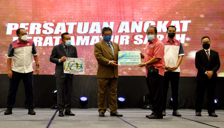 Ellron menyampaikan insentif kepada salah seorang wakil persatuan semasa majlis Penyampaian Insentif Kemenangan Sukan 2020/2021 dan Geran Tahunan Persatuan Sukan Sabah 2022 di SICC pada Selasa.