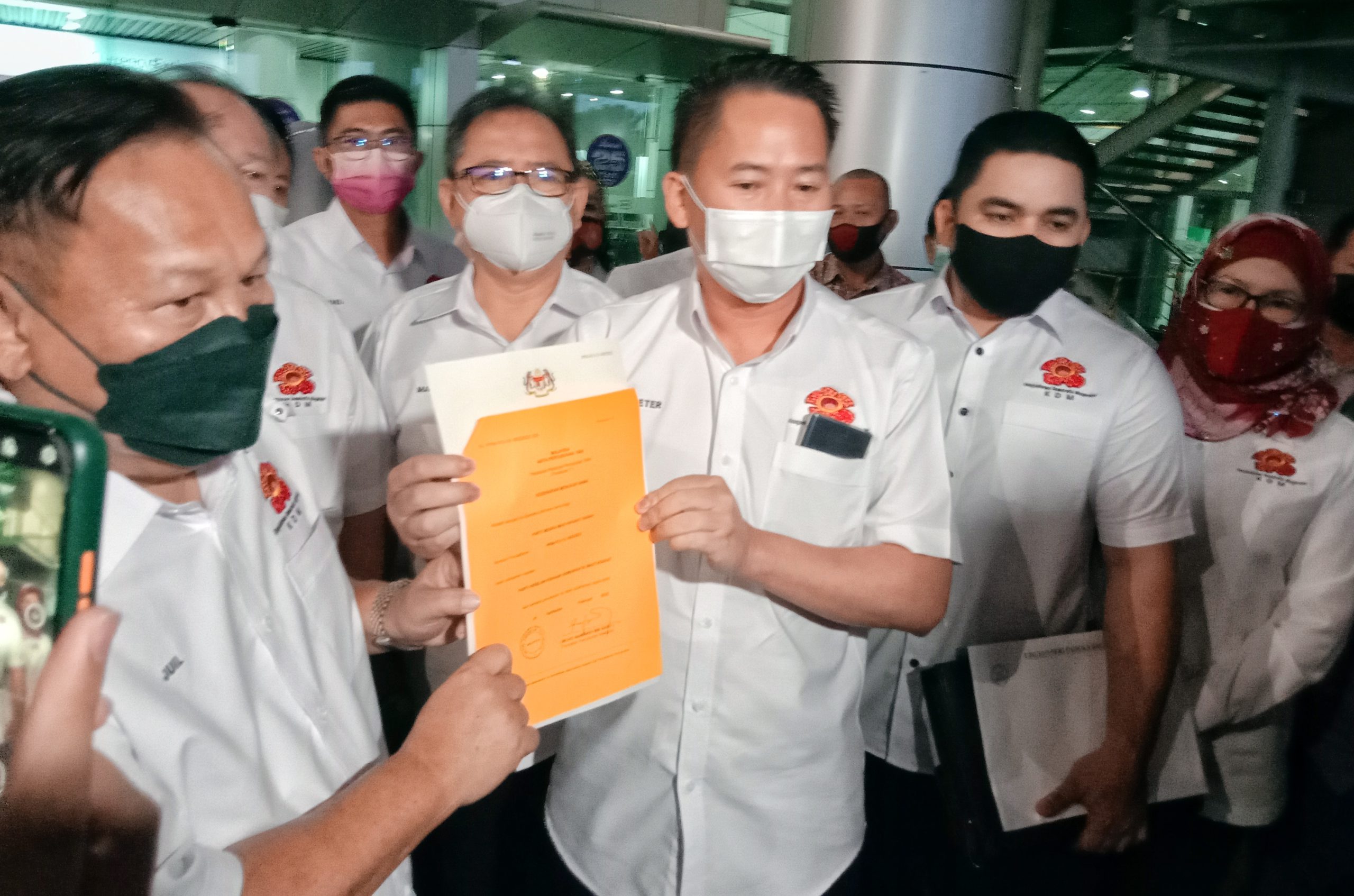 Peter (tengah) menunjukkan dokumen kelulusan ROS parti baharunya Kesejahteraan Demokratik Masyarakat (KDM) semasa sidang media di Lapangan Terbang Antarabangsa Kota Kinabalu petang tadi.