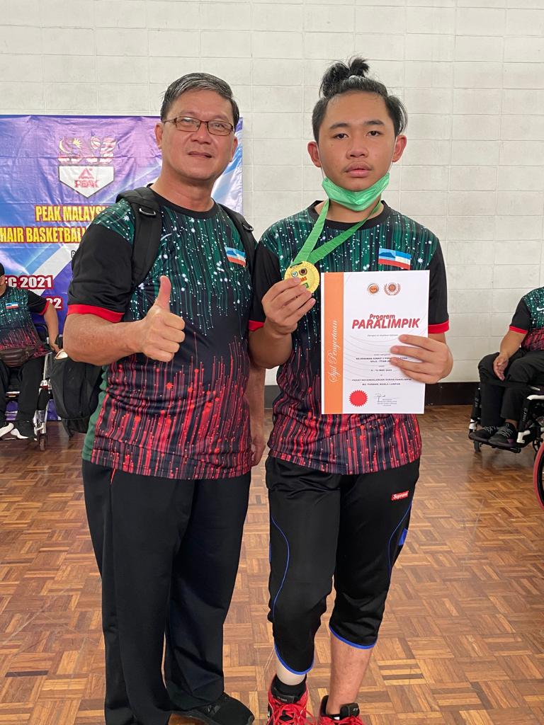 Atlet para Aliff Aldih, 16, ( kanan) menerima pingat emas dalam acara ping pong dan Jurulatih Thien Teck Leong.