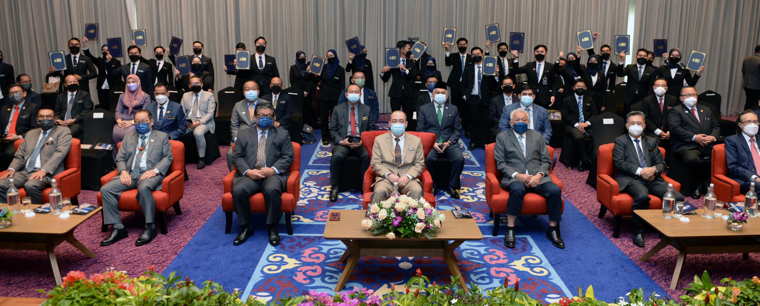 Ketua Menteri Datuk Seri Hajiji Noor (duduk tengah) dan menteri kabinet bersama 24 peserta Felo SMJ di latar belakang menunjukkan surat pelantikan mereka.