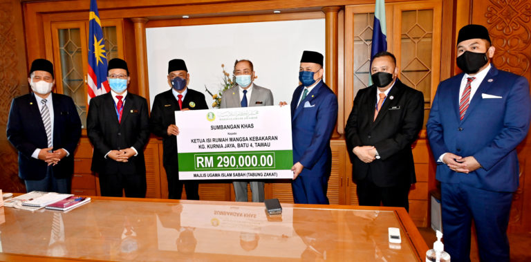 Ketua Menteri, Datuk Seri Hajiji Noor (tengah) menyaksikan penyerahan sumbangan khas MUIS kepada KIR mangsa kebakaran Kg. Kurnia Jaya, Batu 4, Tawau daripada Ustaz Malai Ali Malai Ahmad kepada Datuk Arifin Mohd Arif (tiga dari kanan).