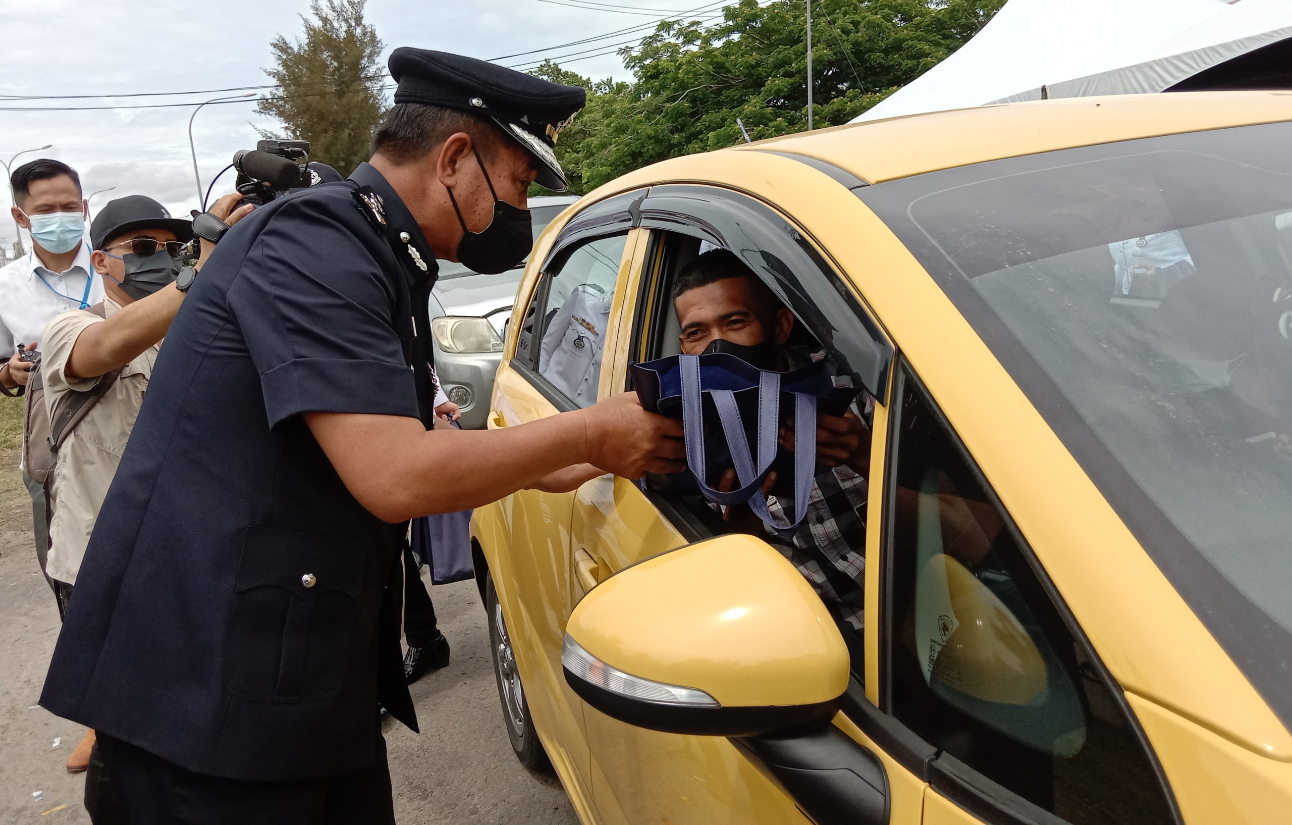 Jauteh mengagihkan 'goodies' kepada pemandu kenderaan awam semasa pelancaran OP SELAMAT 18 di Kg Meruntum Lok Kawi Putatan hari ini.
