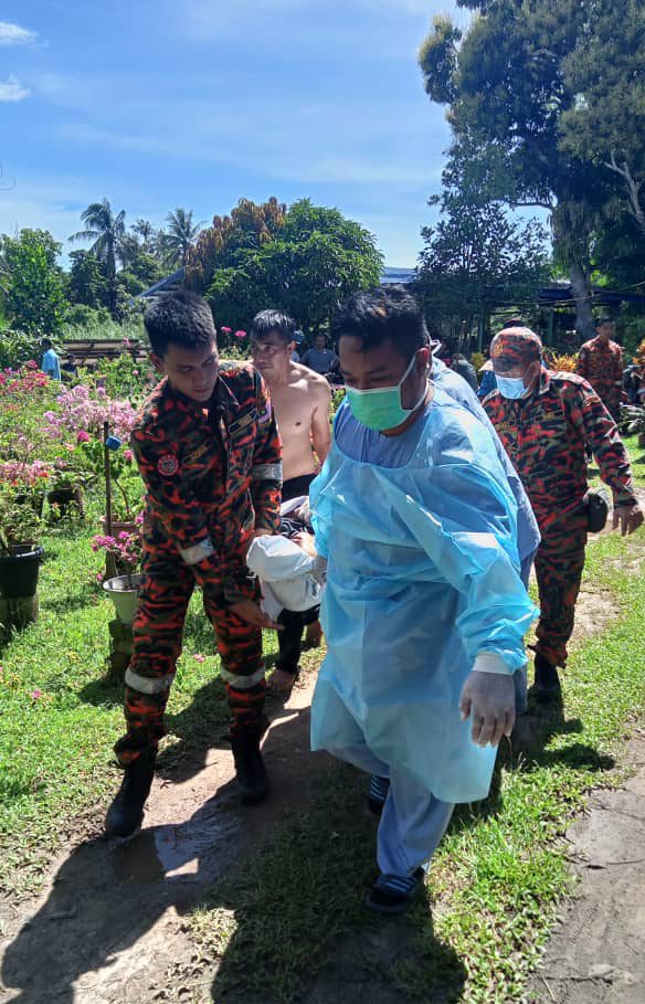Pasukan petugas Bomba dan KKM mengangkat mayat mangsa remaja lelaki yang lemas di Kg Banting Sipitang semalam. - Foto ihsan JPBM Sabah