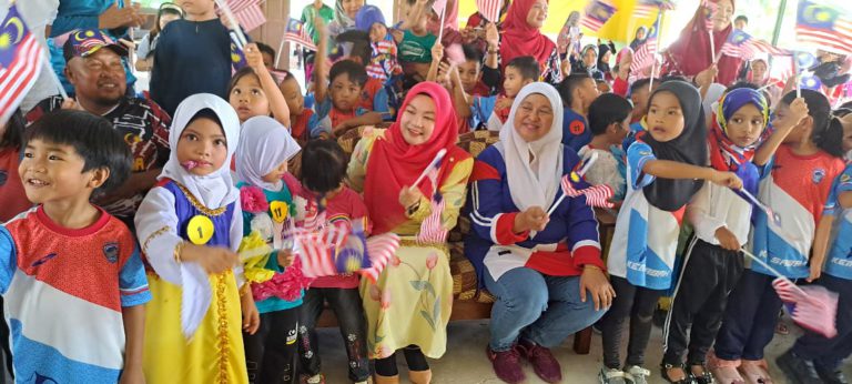 Redonah bergambar kenangan sambil mengibarkan bendera Jalur Gemilang bersama kanak-kanak Tadika Kemas Pekan Lama di Dewan Serbaguna Bandau.